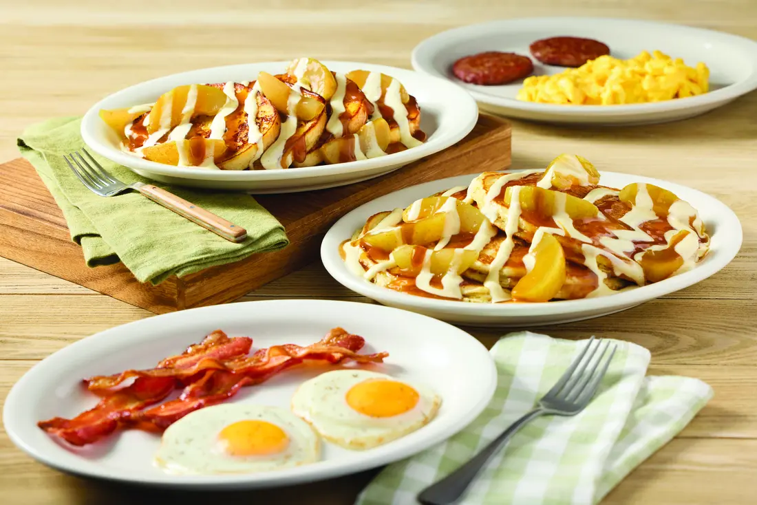 Caramel apple pancakes and French toast served with eggs, sausage, and bacon.